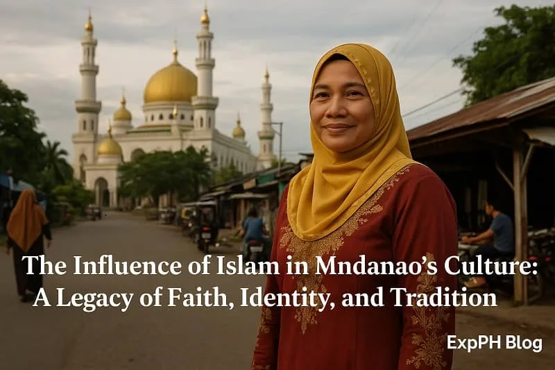 A realistic scene of a Mindanaoan Muslim woman wearing a mustard-yellow hijab and maroon traditional attire standing on a village road with the Grand Mosque of Cotabato in the background, symbolizing the cultural and spiritual heritage of Mindanao. The ExpPH Blog logo appears in the corner of the image.