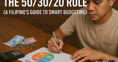 Filipino man writing a budget plan using the 50 30 20 rule with cash, coins, and calculator on a wooden table