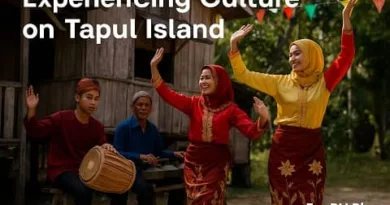 A realistic scene of Tausug performers dancing and playing traditional instruments on Tapul Island, with colorful attire, a wooden stilt house, and the ExpPH Blog logo.