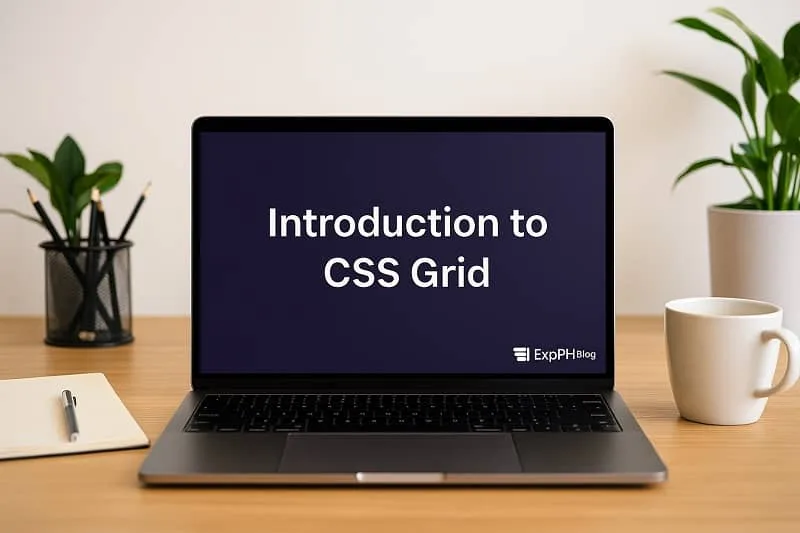 Laptop on a wooden desk showing Introduction to CSS Grid with a small ExpPH Blog logo