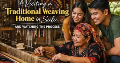 Filipino woman weaving traditional fabric in a Sulu home while visitors watch the weaving process up close