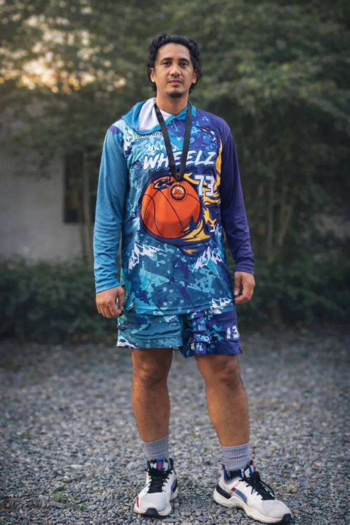 Bioy Ajijul standing outdoors in Concentrix Wheels basketball jersey with medal from Mythical Five award at 2024 Sportfest